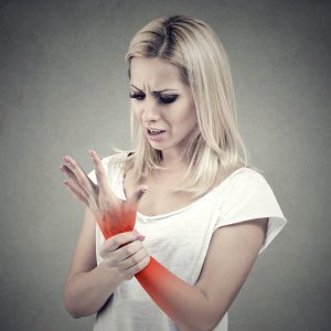 An image of a woman holding her wrist that is highlighted red to promote the medicated patches for pain and inflammation from Frequency Apps.