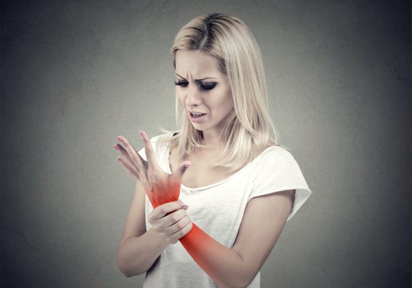 An image of a woman holding her wrist that is highlighted red to promote the medicated patches for pain and inflammation from Frequency Apps.