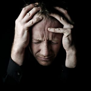 An image of a man grabbing his head showing frustration to promote the homeopathic patches for emotional rescue from Frequency Apps.