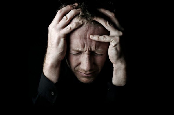 An image of a man grabbing his head showing frustration to promote the homeopathic patches for emotional rescue from Frequency Apps.