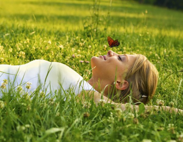 An image of a woman lying in the grass with a butterfly floating over her to promote the homeopathic patches for female hormone balance from Frequency Apps.