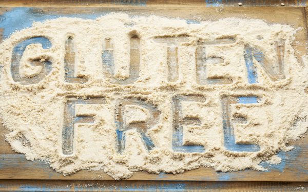 An image of the phrase “Gluten-Free” written with a finger in flour to promote the gluten-free homeopathic patch from Frequency Apps.