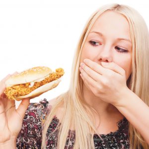 An image of a girl covering her mouth while looking at a sandwich to imply that she doesn’t not want to eat it in order to promote the appetite suppressant medicated patch from Frequency Apps