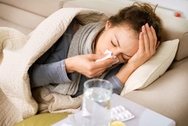 An image of a girl laying on the couch blowing her nose to promote the medicated patches for virus and flu relief from Frequency Apps.